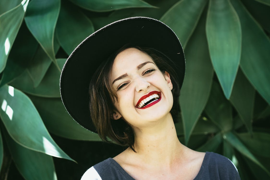Woman Smiling In Front Of Green Plants