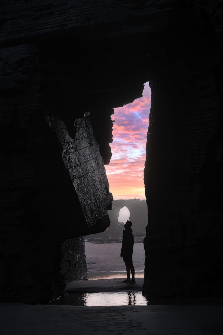 Silhouette Of A Person Standing At The Entrance Of A Beach Cave