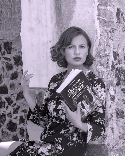 Free A woman is sitting on a bench holding a book Stock Photo