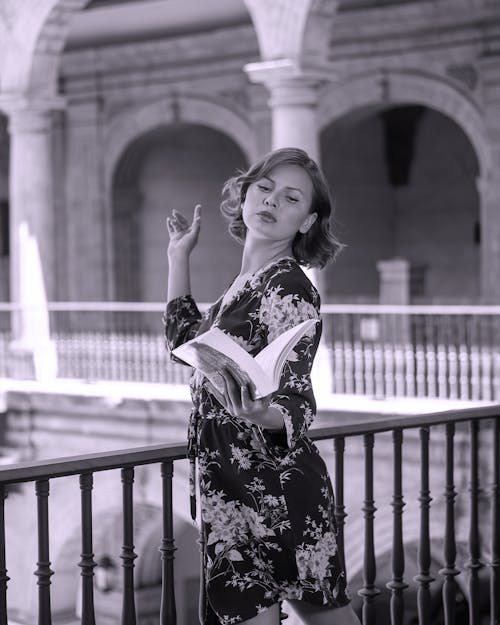 Free A woman in a floral dress is holding a book Stock Photo