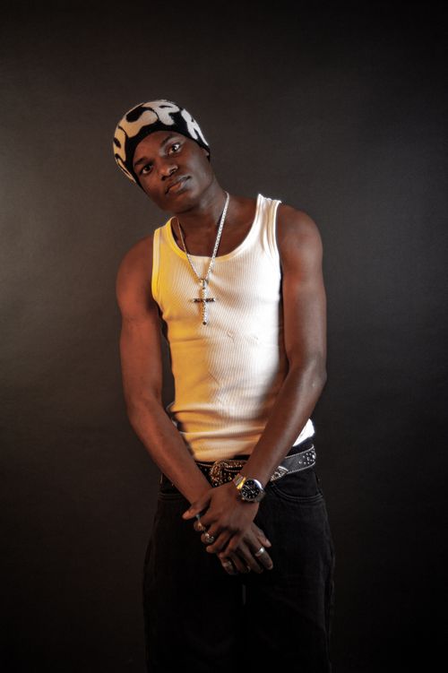 Free Stylish young man in a white tank top and knit hat posing confidently in a studio portrait. Stock Photo