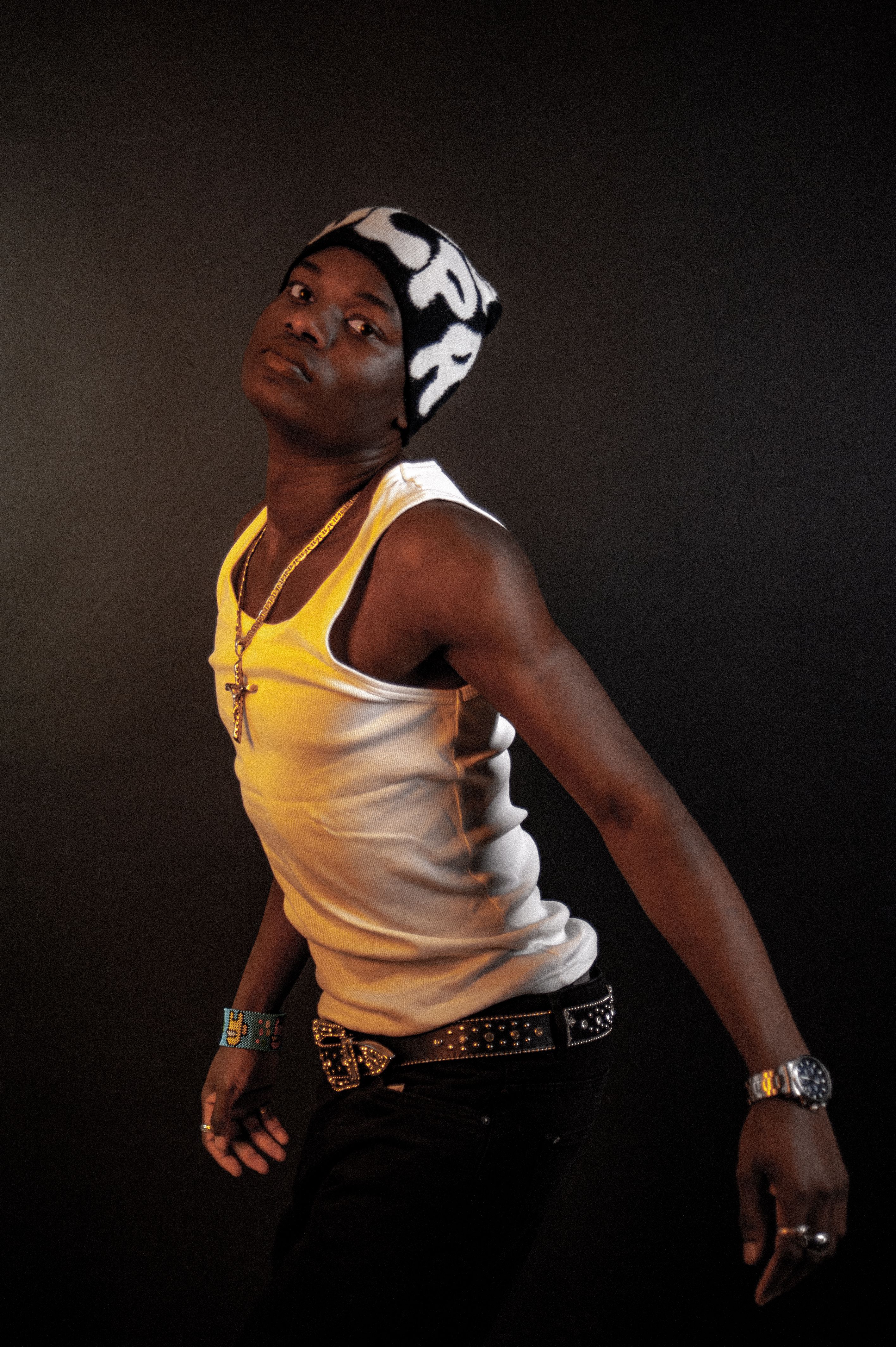 Portrait of a young man in a stylish pose, wearing a white tank top and knit hat.