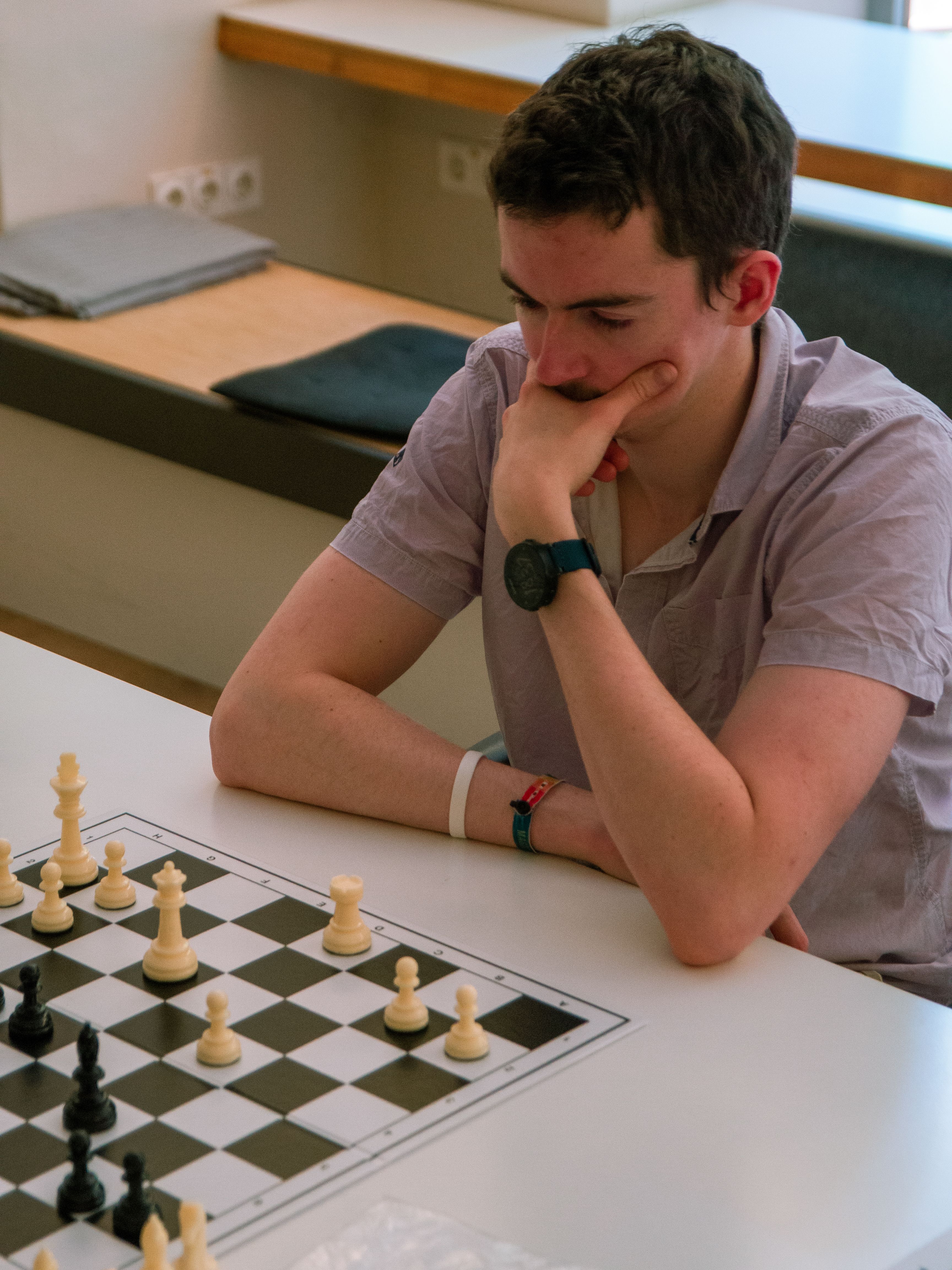 A young Caucasian man deeply focused while playing chess, immersing himself in strategy and contemplation.
