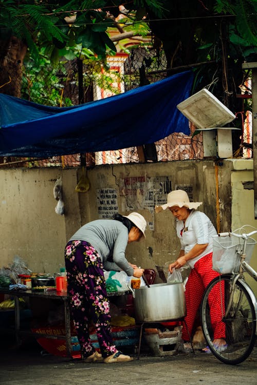 Two women are cooking food in a small kitchen