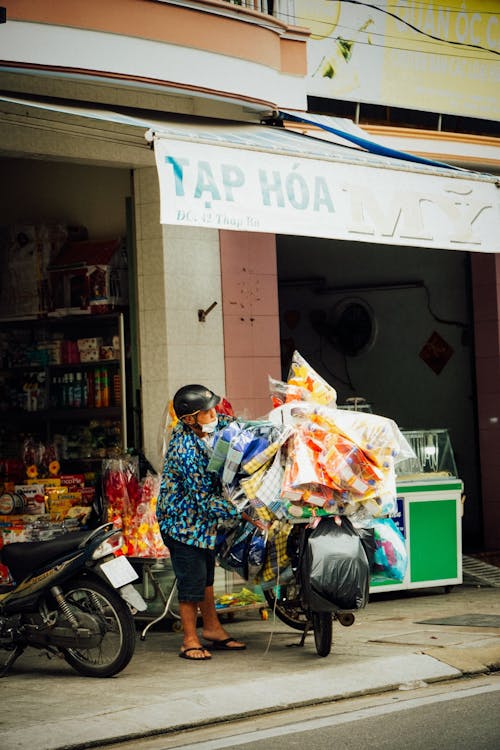 A woman on a motorbike with a bag of groceries