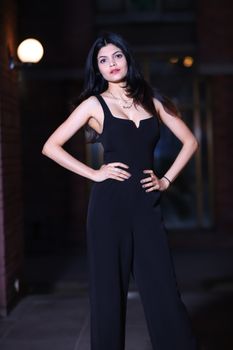 一位身着黑色服装的优雅女子在城市环境中自信地摆出姿势