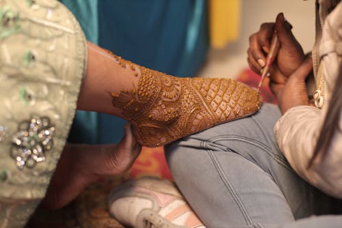 Free A woman is applying henna on a man's feet Stock Photo