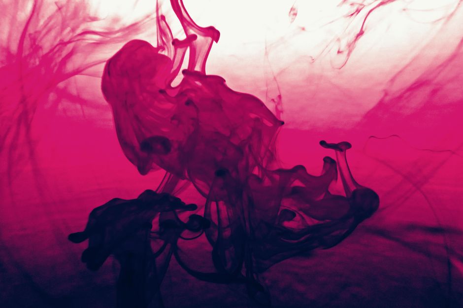 Vibrant abstract artwork featuring swirling pink and red liquid ink patterns.