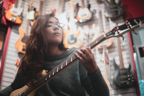 Woman in Gray Sweater Playing Guitar