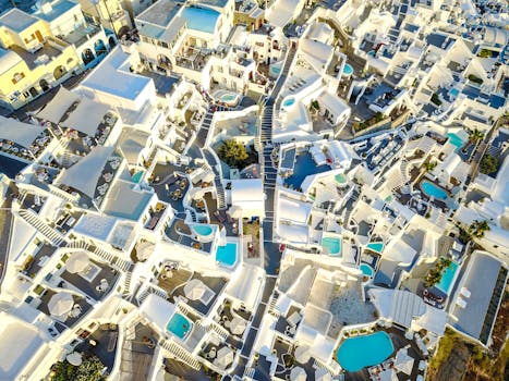 A stunning aerial shot capturing the unique architecture of Thera, Santorini, with vibrant pools and whitewashed buildings.