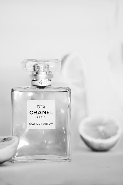 A bottle of chanel perfume sits on a table next to some lemons