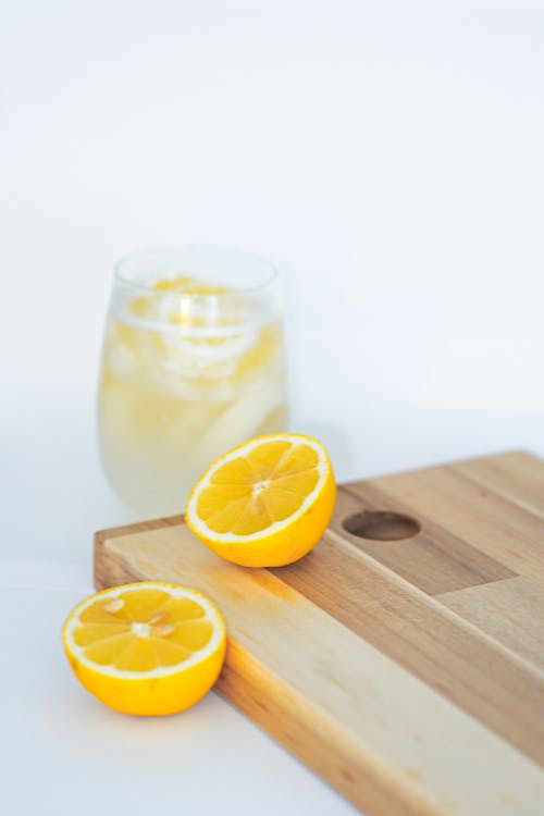 Free A wooden cutting board with two slices of lemon and a glass of lemonade Stock Photo