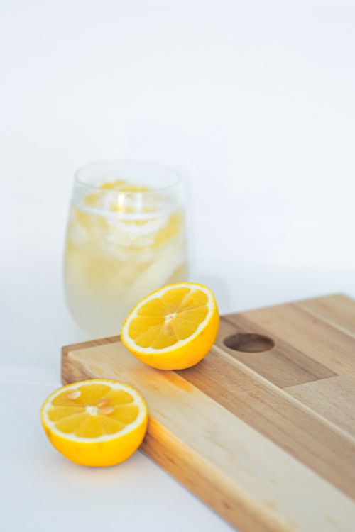 Free Refreshing lemonade with lemon slices on a wooden cutting board, perfect for summer vibes. Stock Photo
