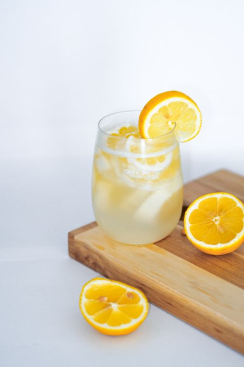 Free Chilled lemonade with lemon slices on a wooden cutting board, captured in a bright and clean setting. Stock Photo