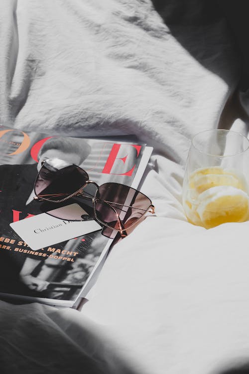 A magazine and sunglasses on a bed