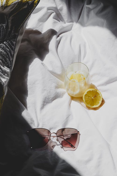 A pair of sunglasses and a lemon on a bed