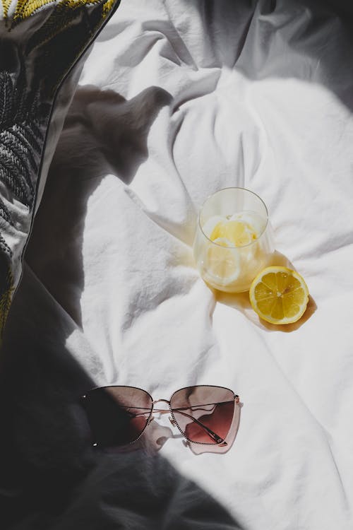 Free A pair of sunglasses and a lemon on a bed Stock Photo