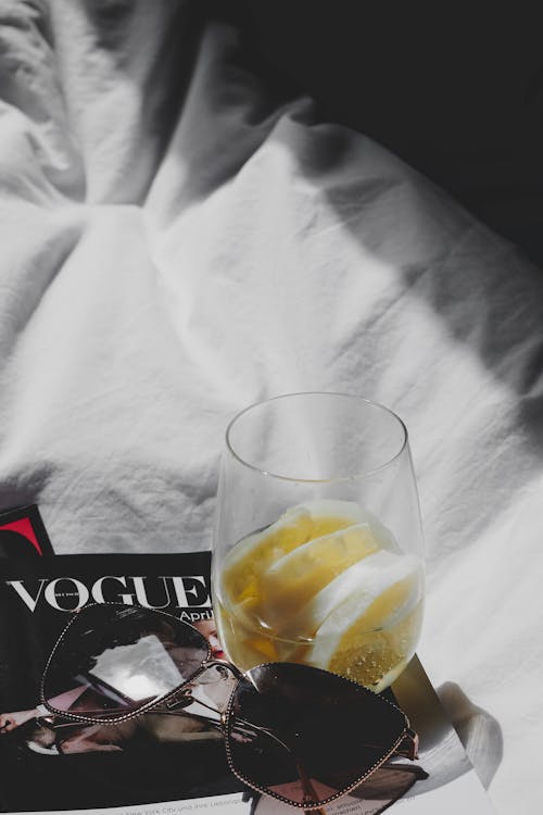 A glass of lemonade and a magazine on a bed