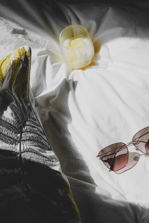 Free A pair of sunglasses laying on a bed with a candle Stock Photo