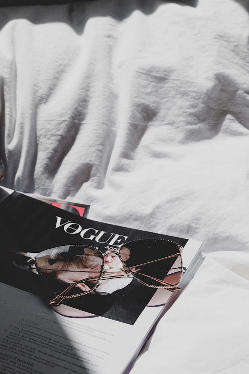 Free A magazine on a bed with glasses and a book Stock Photo