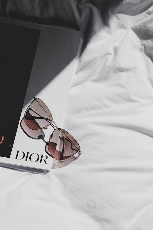 Dior sunglasses on a bed with a magazine