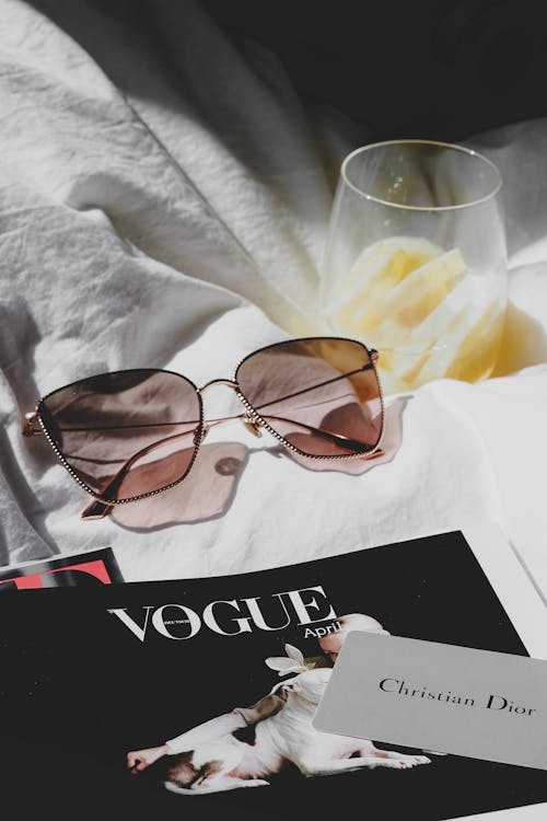 A magazine with sunglasses and a glass of wine