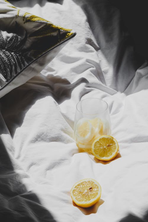 Free A lemon and a glass of water on a bed Stock Photo