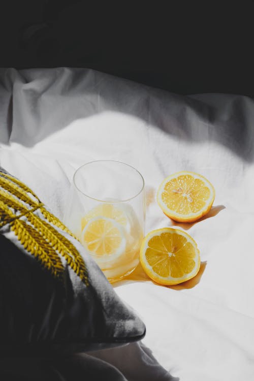 A lemon and glass of water on a bed
