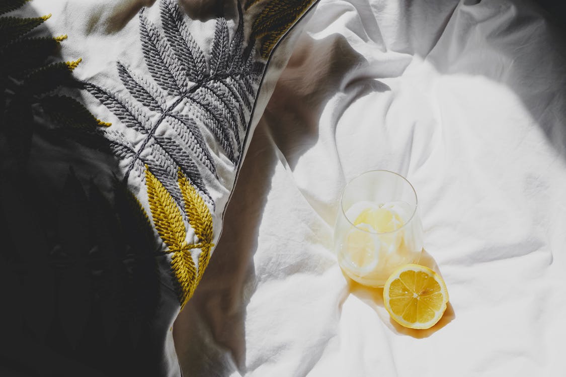 Free A lemon slice and a glass of water on a bed Stock Photo