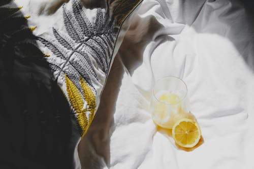 Free A lemon slice and a glass of water on a bed Stock Photo