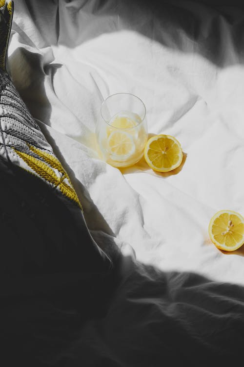 A lemon and glass on a bed with a white sheet