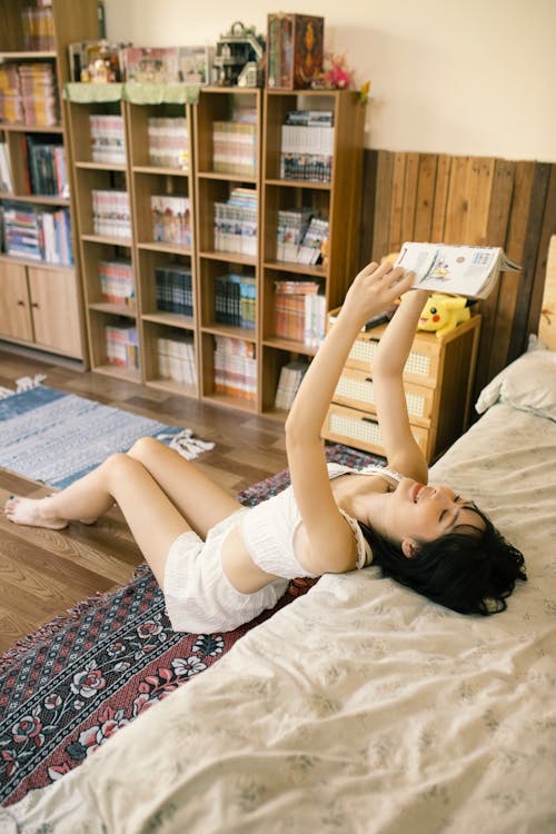 A woman laying on a bed reading a book