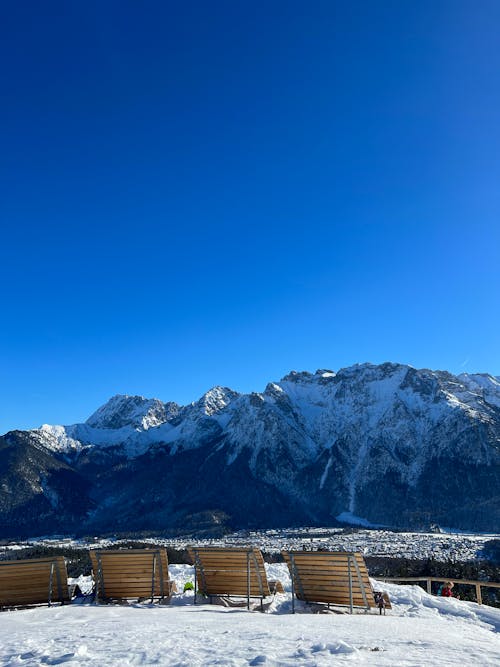 Free A ski slope with wooden benches and snow covered mountains Stock Photo