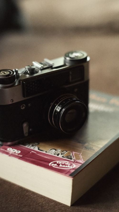 Free A classic vintage camera sits atop a book, evoking nostalgia and retro vibes. Stock Photo