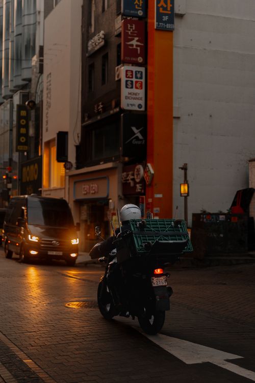 Free Motorcyclist navigating a dimly lit city street at night, amidst vibrant urban environment. Stock Photo