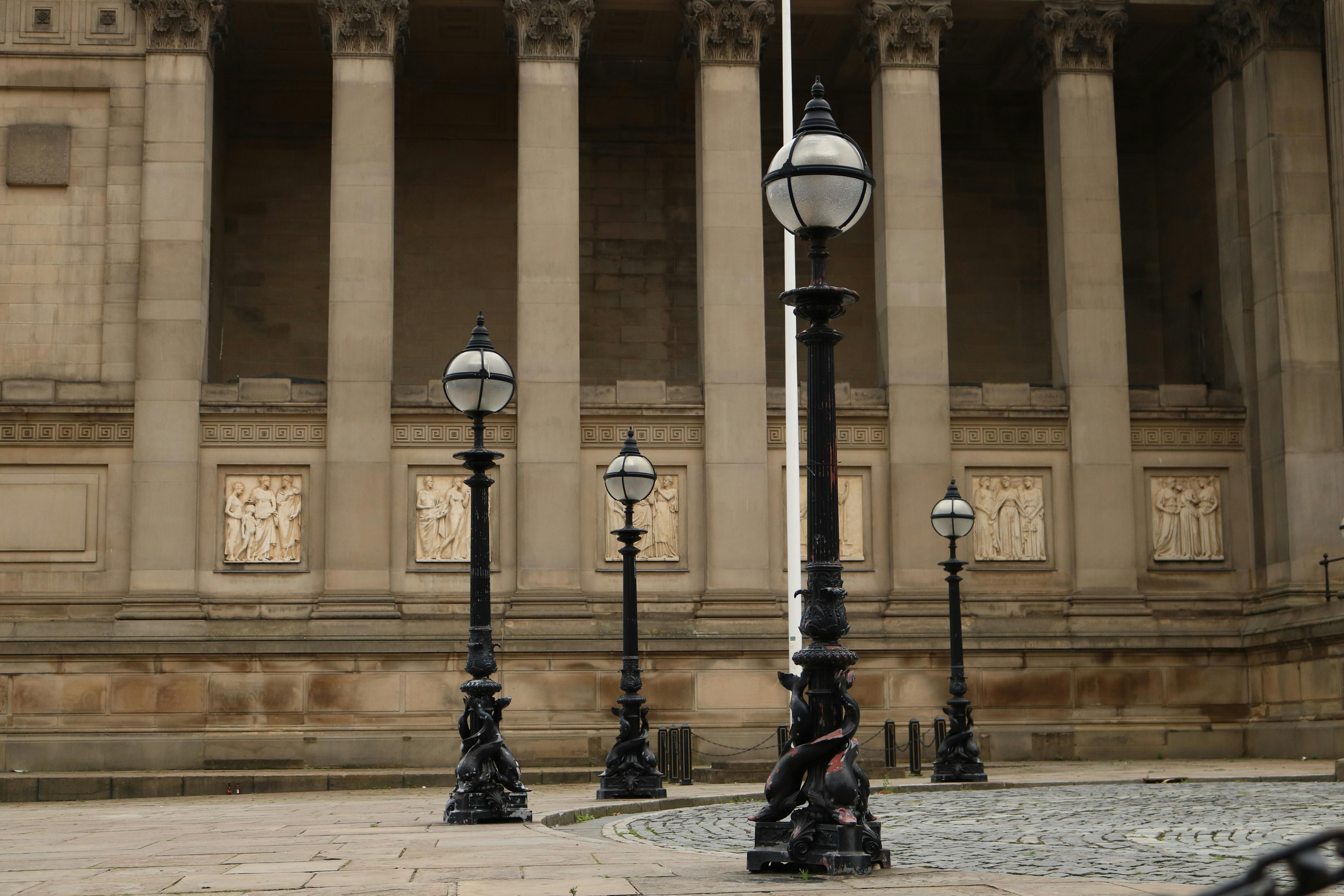 A classical colonnade with vintage street lamps in urban setting.