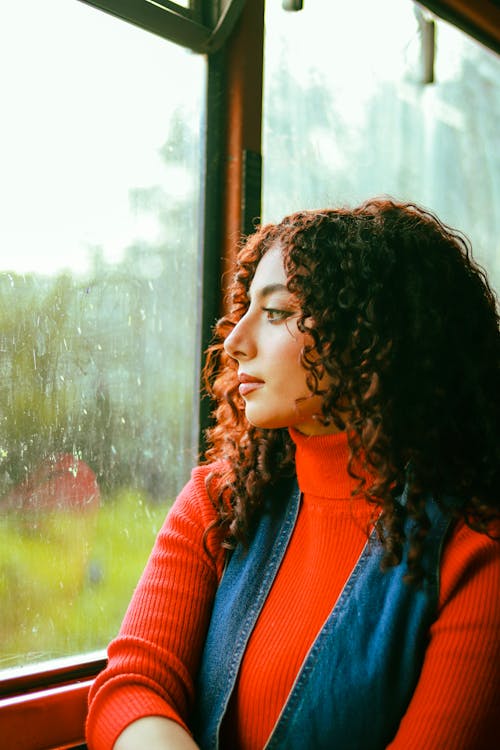 A woman sitting on a train window looking out the window