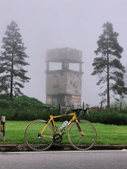 A yellow bike parked in front of a foggy tower