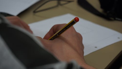 Человек, держащий карандаш на белой бумаге для принтера