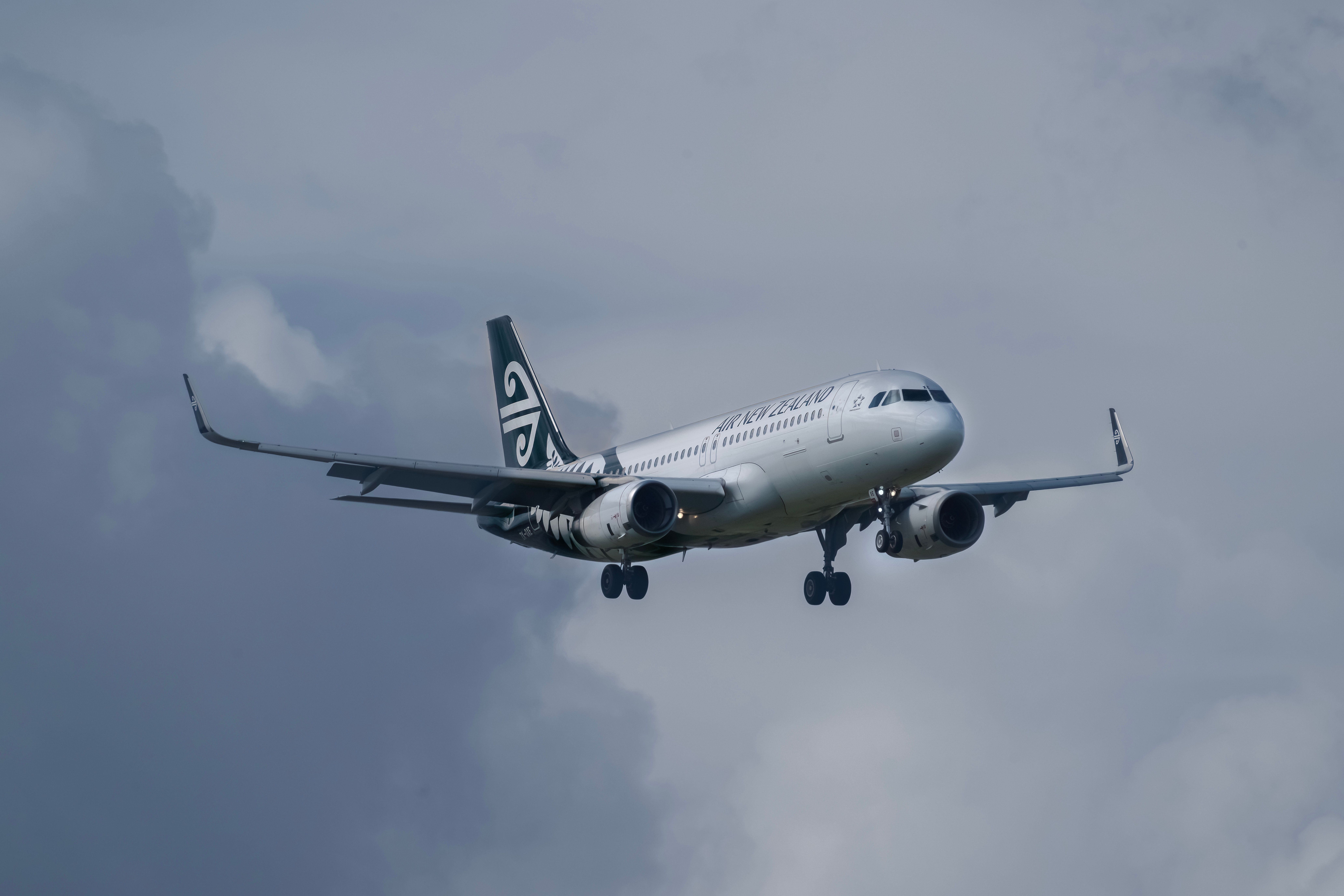 Air New Zealand aircraft flying amidst cloudy sky, showcasing aviation travel.