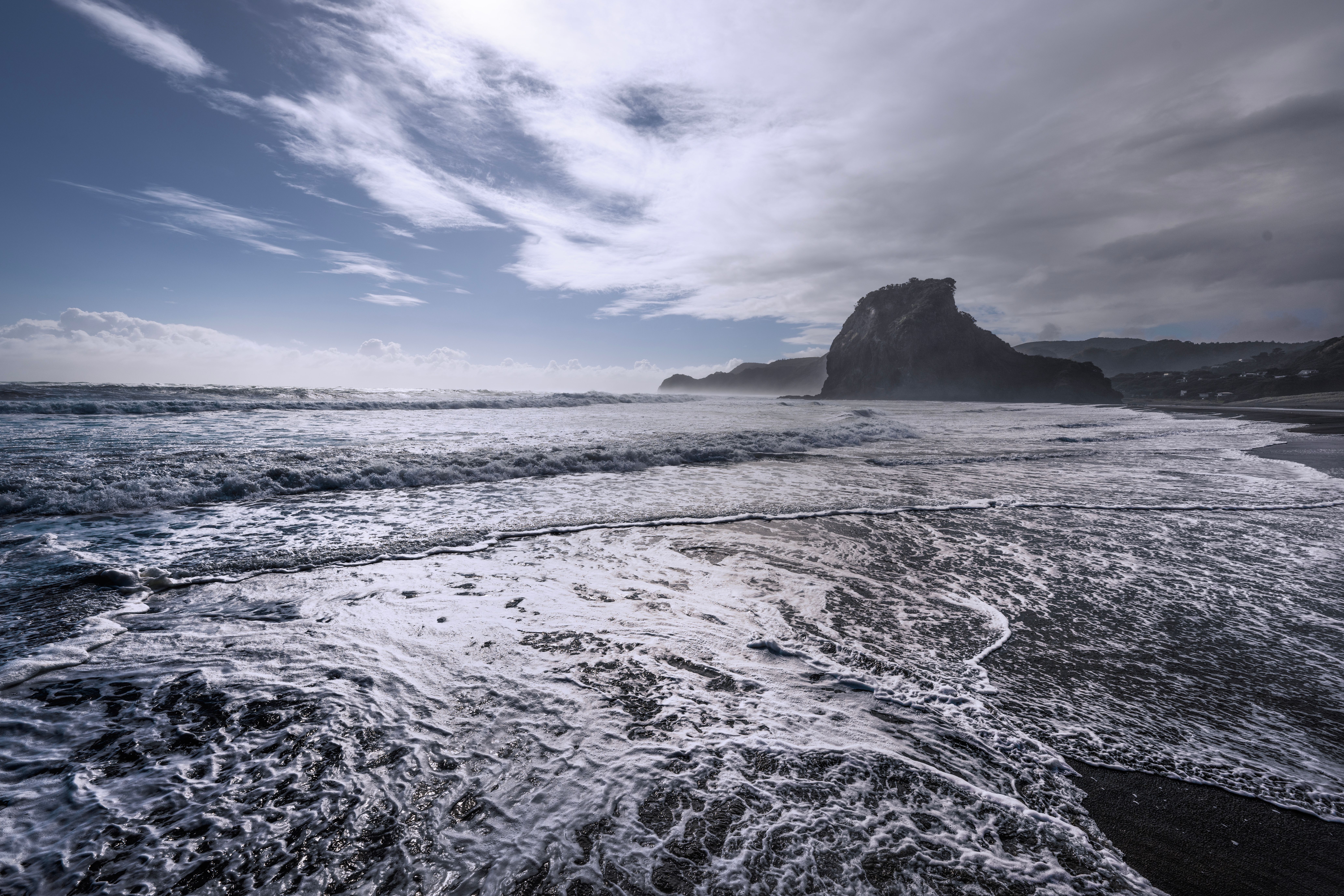 Sea Waves Washing over the Beach with a Rock Formation in the Distance ...