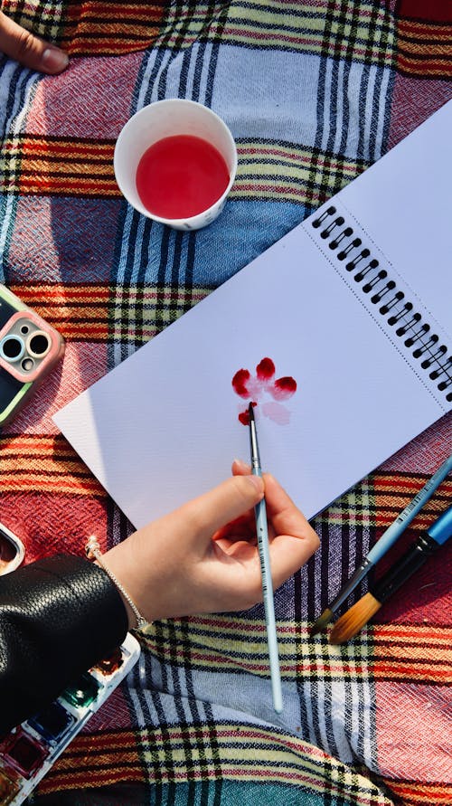 Free A person is drawing on a notebook with watercolor paints Stock Photo