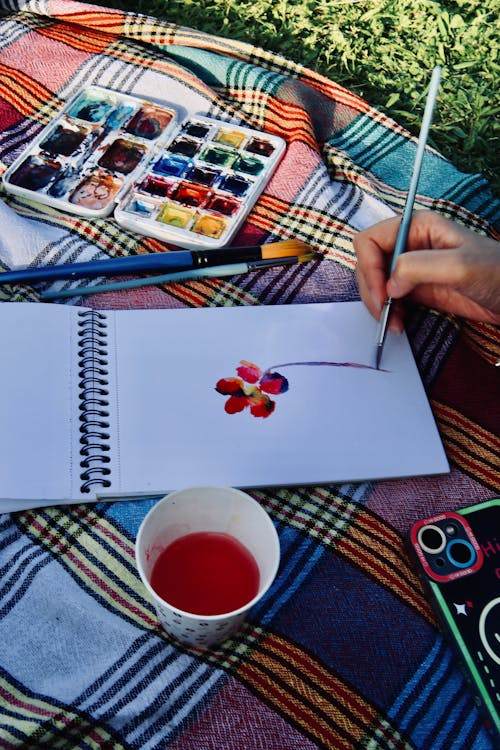 Free A person is drawing on a picnic blanket with watercolor Stock Photo