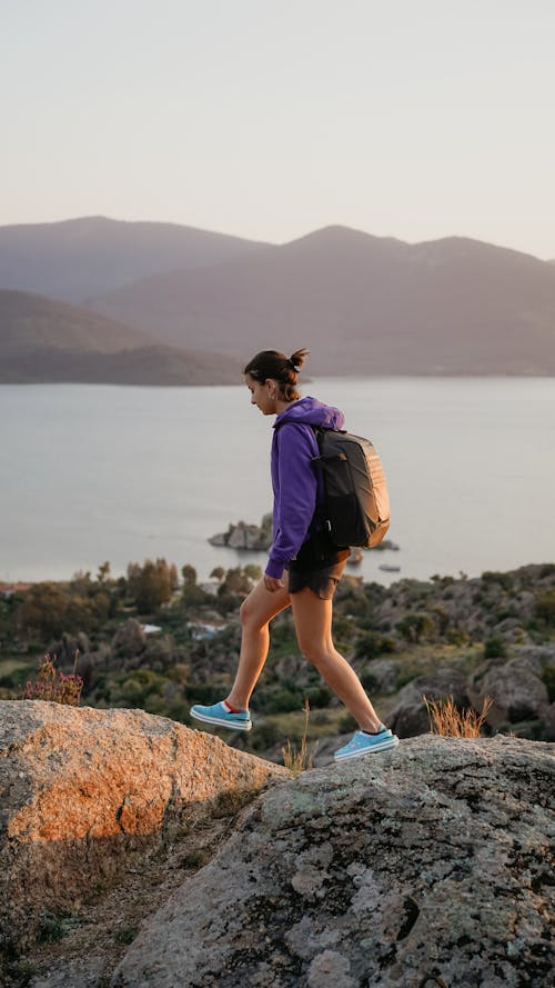 A woman in purple and black hiking gear on a rock