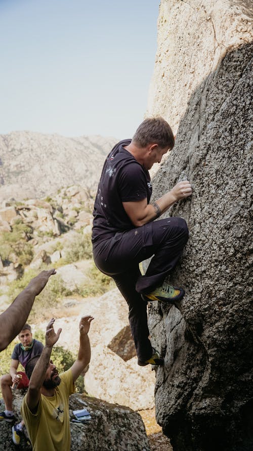A man climbing on a rock with other people