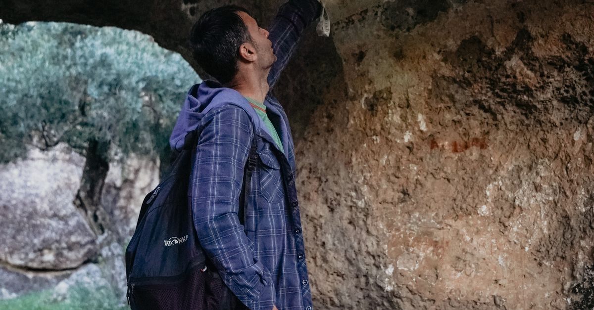 Person Looking Under Rocks Man Looking at Ancient Paintings on Rocks · Free Stock Photo