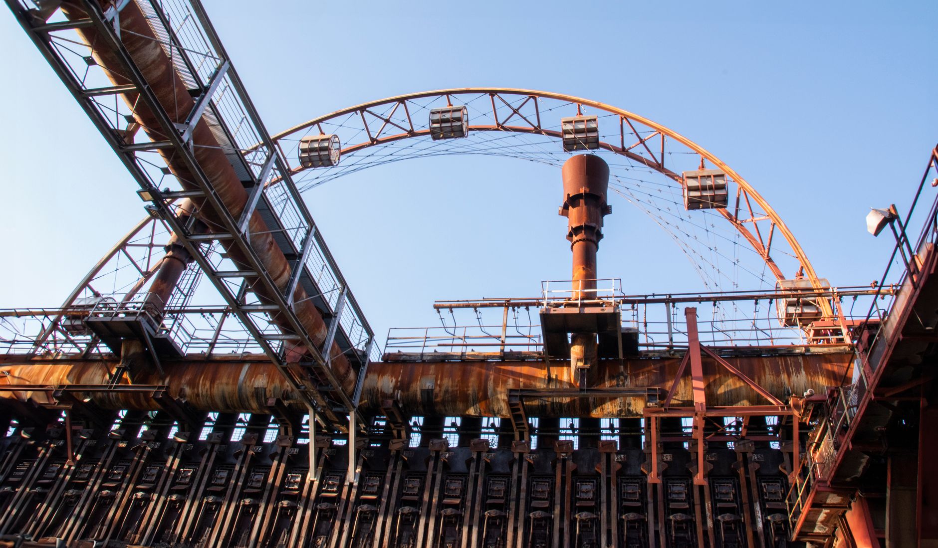 A rusted industrial structure against a clear blue sky at Zollverein, Essen.