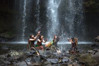 四名女子身着文化服饰，在瀑布旁欢乐玩耍，展现了大自然的美丽