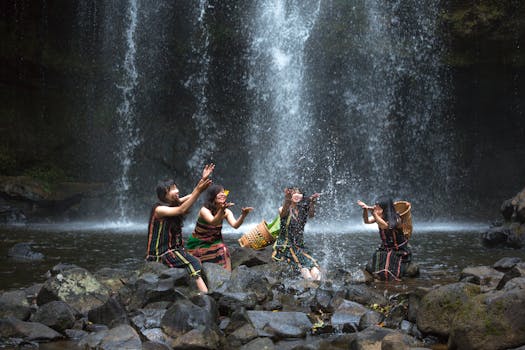四名女子身着文化服饰，在瀑布旁欢乐玩耍，展现了大自然的美丽