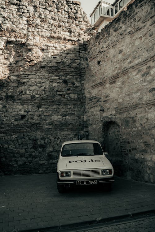 A white car parked in front of a brick wall